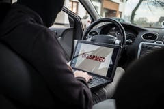 Protecciones de desarme del coche del ladrón de coches con el ordenador portátil fotografía de archivo libre de regalías Protecciones de desarme del coche del ladrón de coches con el ordenador portátil fotografía de archivo libre de regalías
