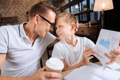 Proud father cuddling son holding printout with charts. Proud of you. Happy young father cuddling his son and pressing his forehead to sons forehead, being proud stock images Proud father cuddling son holding printout with charts. Proud of you. Happy young father cuddling his son and pressing his forehead to sons forehead, being proud stock images