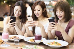 przyjaciele ma go?cia restauracji i ogl?da m?drze telefon w restauracji fotografia stock przyjaciele ma go?cia restauracji i ogl?da m?drze telefon w restauracji fotografia stock
