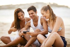 Przyjaciele używa mądrze telefon na plaży obrazy royalty free Przyjaciele używa mądrze telefon na plaży obrazy royalty free