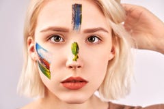 Przyjemna przyglądająca kobieta z pięknym sztuki makeup na twarzy, krótkiego blondynka włosy, pozy przeciw białemu pracownianemu fotografia royalty free Przyjemna przyglądająca kobieta z pięknym sztuki makeup na twarzy, krótkiego blondynka włosy, pozy przeciw białemu pracownianemu fotografia royalty free