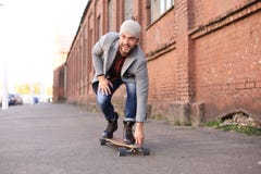 Przystojny m?ody cz?owiek w popielatym ?akiecie i kapeluszu na longboard na ulicie w mie?cie Miastowy je?dzi? na deskorolce poj?c fotografia royalty free Przystojny m?ody cz?owiek w popielatym ?akiecie i kapeluszu na longboard na ulicie w mie?cie Miastowy je?dzi? na deskorolce poj?c fotografia royalty free