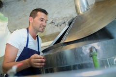 Przystojny piekarniany sprawdza piekarnik przy produkcją zdjęcie stock Przystojny piekarniany sprawdza piekarnik przy produkcją zdjęcie stock