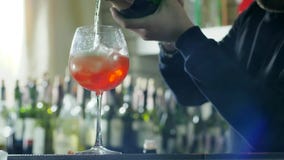 Prętowy pracownik przygotowywa chłodniczego koktajl i nalewa alkohol od butelki w szkle lód i sok, na unfocused tle zbiory Prętowy pracownik przygotowywa chłodniczego koktajl i nalewa alkohol od butelki w szkle lód i sok, na unfocused tle zbiory