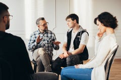 Psychologist talking about twelve-step program to addicted man during group support meeting royalty free stock photos Psychologist talking about twelve-step program to addicted man during group support meeting royalty free stock photos