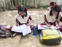 Group of children friends girls classmates studying with book sitting on floor outdoor at the school playground