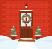 Puerta marrón de la Navidad con la guirnalda, la nieve y abetos en fondo de una pared de ladrillo rojo oscuro La linterna forjada libre illustration Puerta marrón de la Navidad con la guirnalda, la nieve y abetos en fondo de una pared de ladrillo rojo oscuro La linterna forjada libre illustration