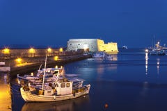 Puerto viejo de Heraklion con la fortaleza de Koules, los barcos y el puerto deportivo venecianos en la noche, Creta fotos de archivo libres de regalías Puerto viejo de Heraklion con la fortaleza de Koules, los barcos y el puerto deportivo venecianos en la noche, Creta fotos de archivo libres de regalías