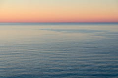 Puesta del sol pacífica por el mar Agua tranquila, cielo brillante Fotografía de archivo Puesta del sol pacífica por el mar Agua tranquila, cielo brillante Fotografía de archivo