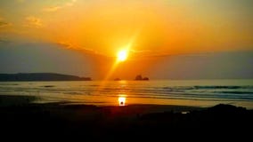Puesta del sol y pares en la distancia que mira cerca de la costa imágenes de archivo libres de regalías Puesta del sol y pares en la distancia que mira cerca de la costa imágenes de archivo libres de regalías