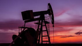 Puits fonctionnant de pétrole et de gaz profilé sur le ciel de coucher du soleil image libre de droits Puits fonctionnant de pétrole et de gaz profilé sur le ciel de coucher du soleil image libre de droits