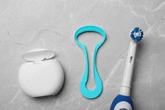Pulitore della lingua, filo per i denti e spazzolino da denti elettrico su fondo grigio fotografia stock libera da diritti Pulitore della lingua, filo per i denti e spazzolino da denti elettrico su fondo grigio fotografia stock libera da diritti