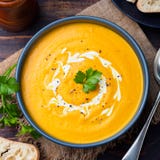 Pumpkin and carrot soup with cream and parsley on dark wooden background Top view stock photos Pumpkin and carrot soup with cream and parsley on dark wooden background Top view stock photos
