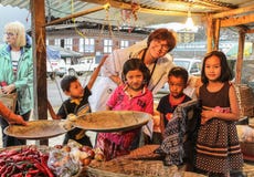 Punakha, Бутан - 10-ое сентября 2016: Счастливая кавказская женщина представляя с бутанскими детьми в базаре с желтым светом в Pu стоковые изображения rf Punakha, Бутан - 10-ое сентября 2016: Счастливая кавказская женщина представляя с бутанскими детьми в базаре с желтым светом в Pu стоковые изображения rf