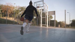 Punto di vista raro di un giocatore di pallacanestro della ragazza che si prepara e che si esercita all'aperto sulla corte locale Punto di vista raro di un giocatore di pallacanestro della ragazza che si prepara e che si esercita all'aperto sulla corte locale
