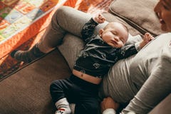 Punto di vista superiore di un bambino che dorme nel rivestimento di sua madre immagini stock libere da diritti Punto di vista superiore di un bambino che dorme nel rivestimento di sua madre immagini stock libere da diritti