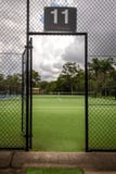 Punto di vista di un campo da tennis tramite il portone aperto in un recinto alla corte fotografia stock Punto di vista di un campo da tennis tramite il portone aperto in un recinto alla corte fotografia stock