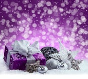 Purple Christmas package , gift of a silver ribbon. Jingle bells , silver christmas balls and christmas stars put on snow. Abstrac Royalty Free Stock Photos Purple Christmas package , gift of a silver ribbon. Jingle bells , silver christmas balls and christmas stars put on snow. Abstrac Royalty Free Stock Photos