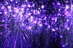 Purple sparkling fireworks exploding in black night sky