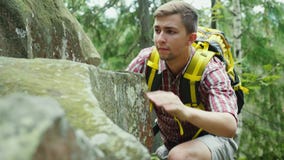 Purposeful man with a backpack climbs on a rock. Concept - the pursuit of a goal