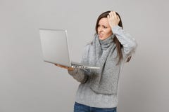 Puzzled young woman in gray sweater, scarf putting hand on head working on laptop pc computer isolated on grey wall royalty free stock images Puzzled young woman in gray sweater, scarf putting hand on head working on laptop pc computer isolated on grey wall royalty free stock images