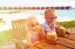Pys- och litet barnflicka som dricker kokosnötcoctailen på stranden royaltyfri bild Pys- och litet barnflicka som dricker kokosnötcoctailen på stranden royaltyfri bild