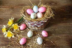 Påskägg i en korg som dekoreras med sugrör och pingstliljan på en trälantlig bakgrund royaltyfri bild Påskägg i en korg som dekoreras med sugrör och pingstliljan på en trälantlig bakgrund royaltyfri bild