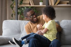 Père africain chatouillant le petit fils adorable ayant l'amusement à la maison images stock Père africain chatouillant le petit fils adorable ayant l'amusement à la maison images stock