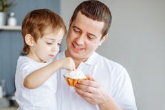 Père alimentant son petit fils dans la cuisine photographie stock libre de droits Père alimentant son petit fils dans la cuisine photographie stock libre de droits