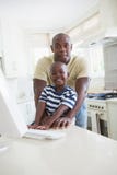 Père de sourire heureux avec son fils à l'aide de l'ordinateur Photo stock Père de sourire heureux avec son fils à l'aide de l'ordinateur Photo stock