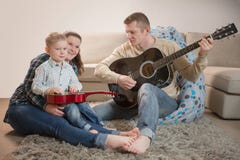 Père heureux et famille jouant des guitares à la maison photographie stock Père heureux et famille jouant des guitares à la maison photographie stock