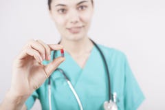 Píldora joven de la tenencia de la mano del doctor en fondo gris foto de archivo libre de regalías Píldora joven de la tenencia de la mano del doctor en fondo gris foto de archivo libre de regalías
