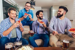 Quatre amis masculins buvant de la bi?re et mangeant de la pizza ? la maison photos libres de droits Quatre amis masculins buvant de la bi?re et mangeant de la pizza ? la maison photos libres de droits