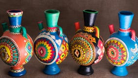Quatre ont décoré les cruches handcrafted colorées de poterie sur le Ba de toile à sac photo stock Quatre ont décoré les cruches handcrafted colorées de poterie sur le Ba de toile à sac photo stock
