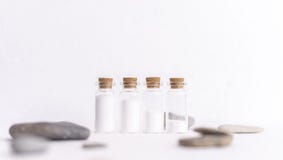 Quatro garrafas pequenas enchidas com o pó branco imagens de stock Quatro garrafas pequenas enchidas com o pó branco imagens de stock