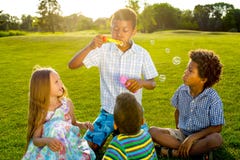 Quattro bambini sulla radura con la bolla di sapone fotografia stock Quattro bambini sulla radura con la bolla di sapone fotografia stock