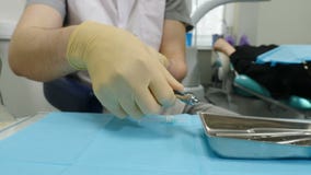 r Ο οδοντίατρος προετοιμάζει τη σύριγγα για την έγχυση της αναισθησίας με το θολωμένο ασθενή στο υπόβαθρο φιλμ μικρού μήκους r Ο οδοντίατρος προετοιμάζει τη σύριγγα για την έγχυση της αναισθησίας με το θολωμένο ασθενή στο υπόβαθρο φιλμ μικρού μήκους