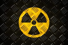 Radiação ionizante radioativa em volta do símbolo amarelo e preto do perigo pintado em uma placa de aço maciça do diamante do met imagens de stock Radiação ionizante radioativa em volta do símbolo amarelo e preto do perigo pintado em uma placa de aço maciça do diamante do met imagens de stock
