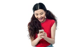 Ragazza abbastanza cinese che legge messaggio divertente fotografie stock Ragazza abbastanza cinese che legge messaggio divertente fotografie stock