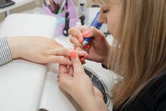 Ragazza al padrone di servizio del chiodo Pulendo e livellando la cuticola della macchina per la frantumazione sulle sue mani fotografie stock Ragazza al padrone di servizio del chiodo Pulendo e livellando la cuticola della macchina per la frantumazione sulle sue mani fotografie stock