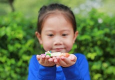 Ragazza asiatica del bambino che tiene una certa caramella tailandese della frutta e dello zucchero con imballato con carte vario immagine stock Ragazza asiatica del bambino che tiene una certa caramella tailandese della frutta e dello zucchero con imballato con carte vario immagine stock
