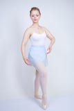Ragazza caucasica sveglia in vestiti di balletto che impara essere una ballerina su un fondo bianco nello studio più i sogni dell immagine stock Ragazza caucasica sveglia in vestiti di balletto che impara essere una ballerina su un fondo bianco nello studio più i sogni dell immagine stock