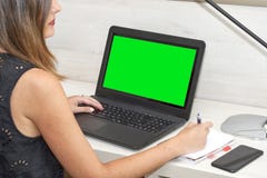 Ragazza che lavora con un taccuino allo scrittorio verde chiave di intensità immagini stock libere da diritti Ragazza che lavora con un taccuino allo scrittorio verde chiave di intensità immagini stock libere da diritti