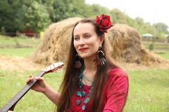 Ragazza con una chitarra e una rosa rossa in suoi capelli immagine stock Ragazza con una chitarra e una rosa rossa in suoi capelli immagine stock