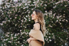 Ragazza di modello bionda alla moda e sensuale con il bello sorriso in cappotto senza maniche ed in occhiali da sole alla moda immagine stock libera da diritti Ragazza di modello bionda alla moda e sensuale con il bello sorriso in cappotto senza maniche ed in occhiali da sole alla moda immagine stock libera da diritti