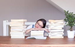 Ragazza divertente sveglia della Tween in vetri stanchi di lettura e di studio del sonno pacificamente con la sua testa sui libri fotografia stock Ragazza divertente sveglia della Tween in vetri stanchi di lettura e di studio del sonno pacificamente con la sua testa sui libri fotografia stock