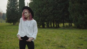 Ragazza graziosa con i supporti alla moda di sguardo nelle pose alla macchina fotografica al parco video d archivio Ragazza graziosa con i supporti alla moda di sguardo nelle pose alla macchina fotografica al parco video d archivio