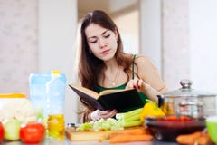 Ragazza premurosa che cucina con il libro di cucina fotografie stock Ragazza premurosa che cucina con il libro di cucina fotografie stock