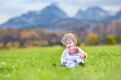 Ragazza riccia sveglia del bambino e suo il fratello del neonato che giocano dentro fotografia stock libera da diritti Ragazza riccia sveglia del bambino e suo il fratello del neonato che giocano dentro fotografia stock libera da diritti