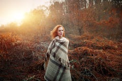 Ragazza rossa dei capelli ad alba avvolta in una coperta rossa fotografia stock Ragazza rossa dei capelli ad alba avvolta in una coperta rossa fotografia stock